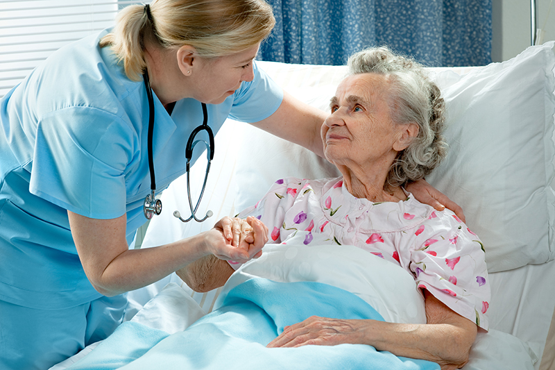 content-v3-img (1) Nurse in blue scrubs comforting an elderly woman resting in an Atlanta hospital bed