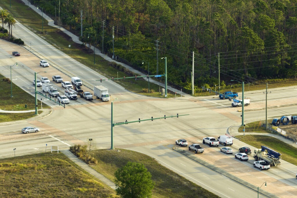 Aerial view of a busy intersection with cars and trucks waiting in left-turn and through lanes.